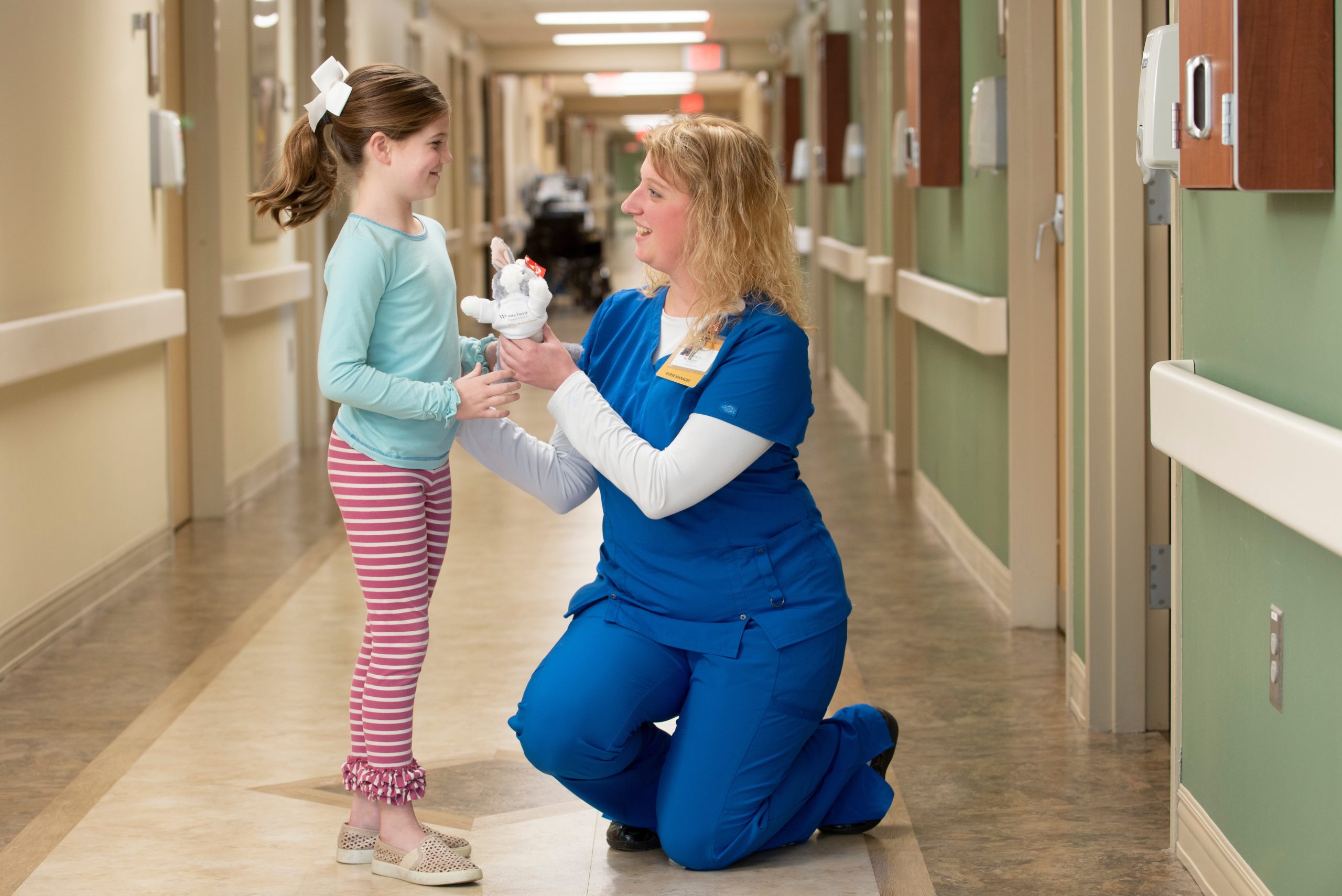 Nurse assisting child in hallway