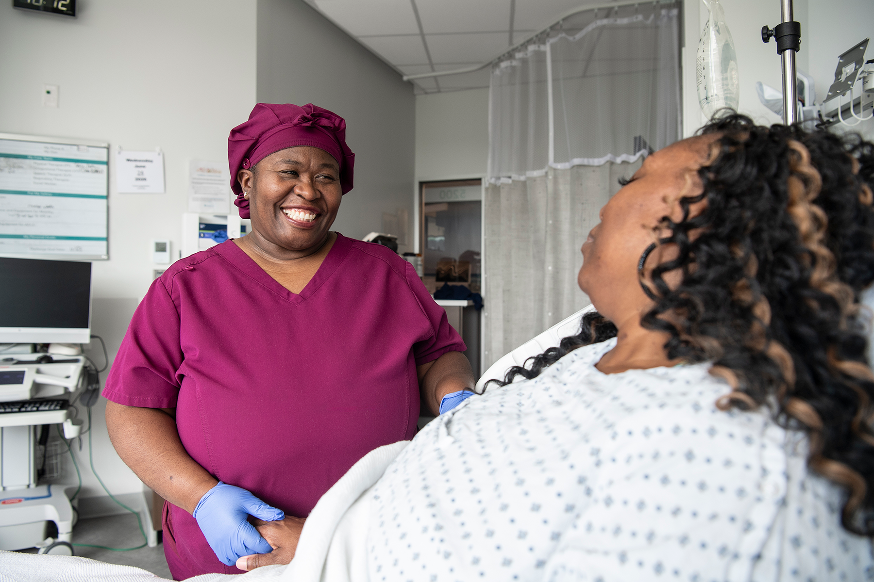 advocate-health-nurse-smiling-at-patient Nurse smiling at patient in hospital bed