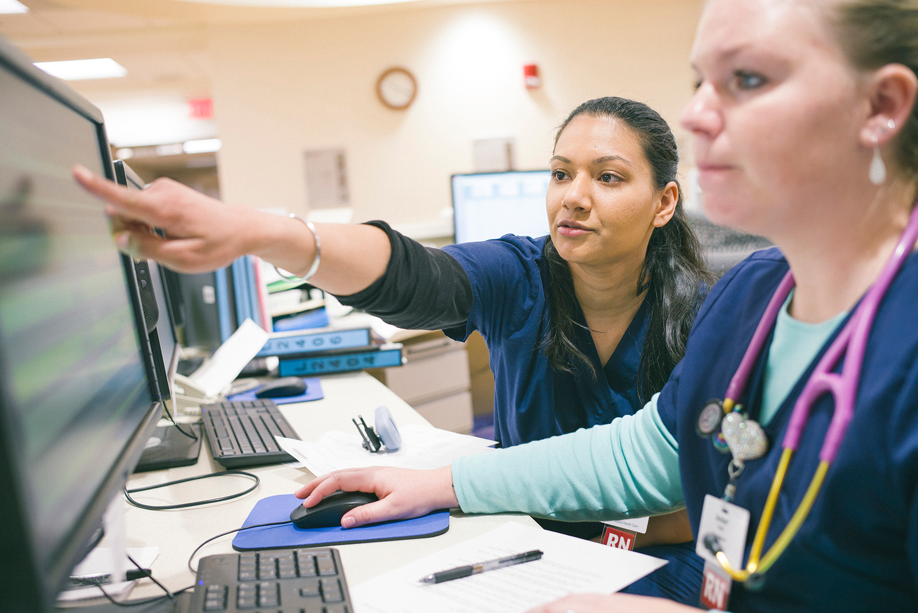 Senior nurse teaching junior nurse at charting station