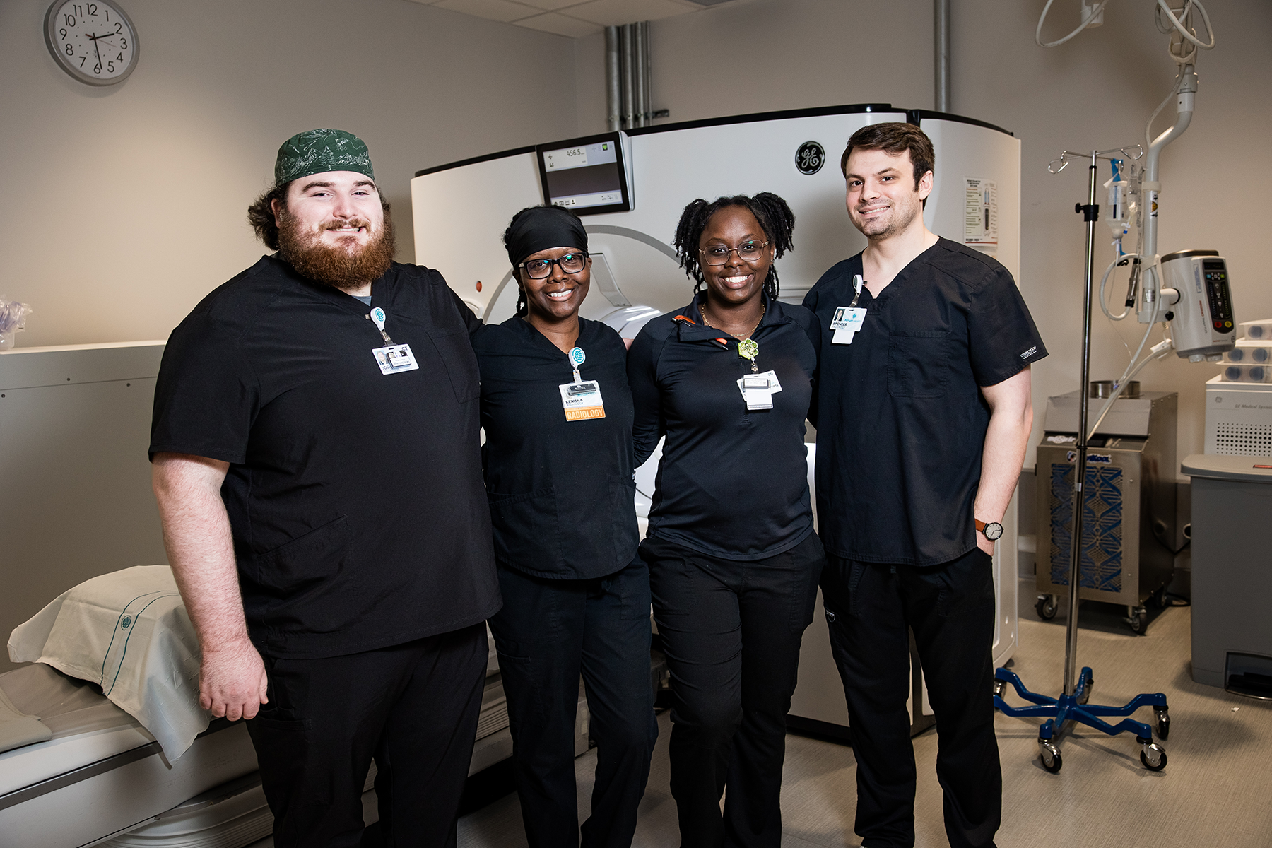 Group of four radiology staff in front of CT machine