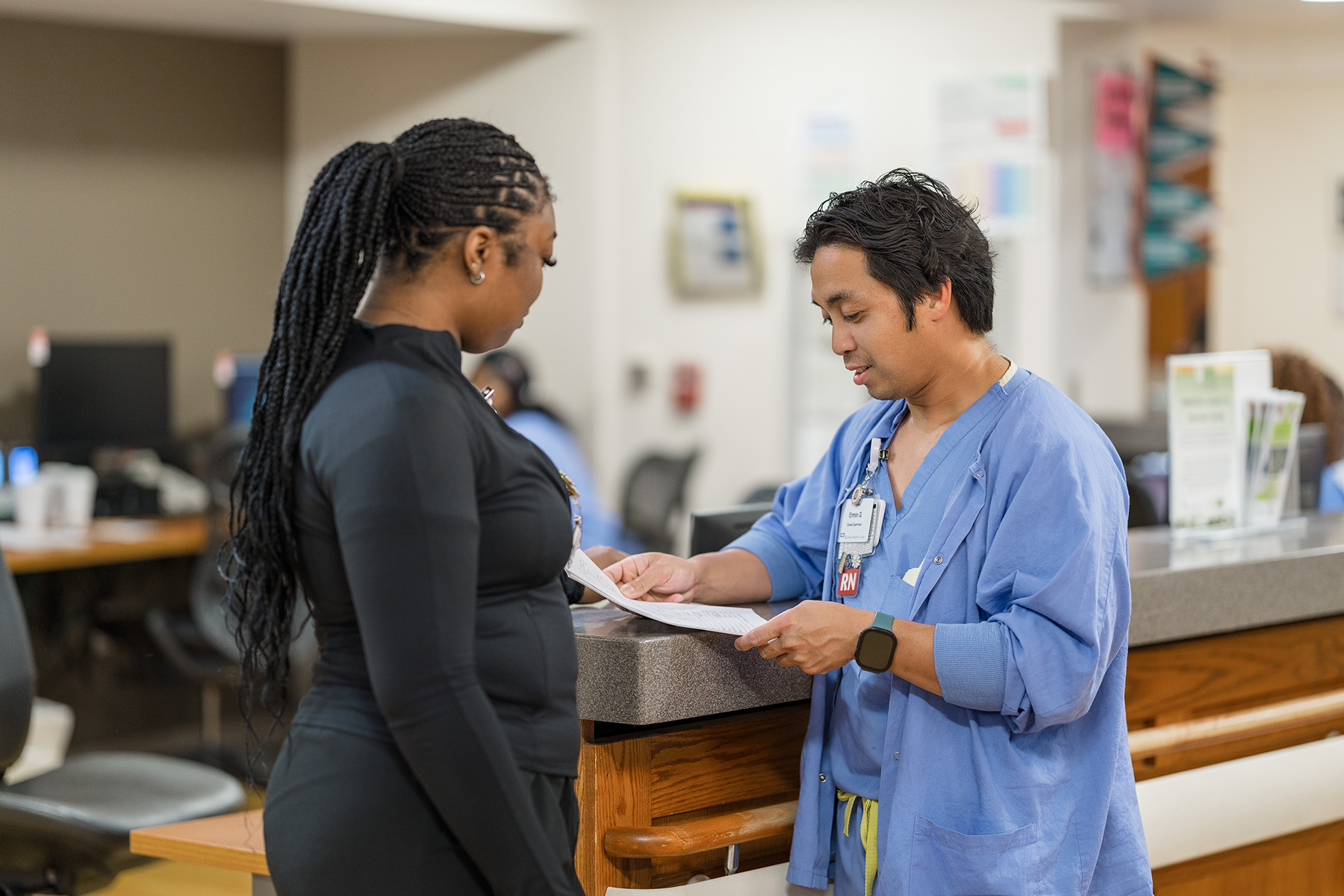 Two clinical staff members reviewing notes at nurses station