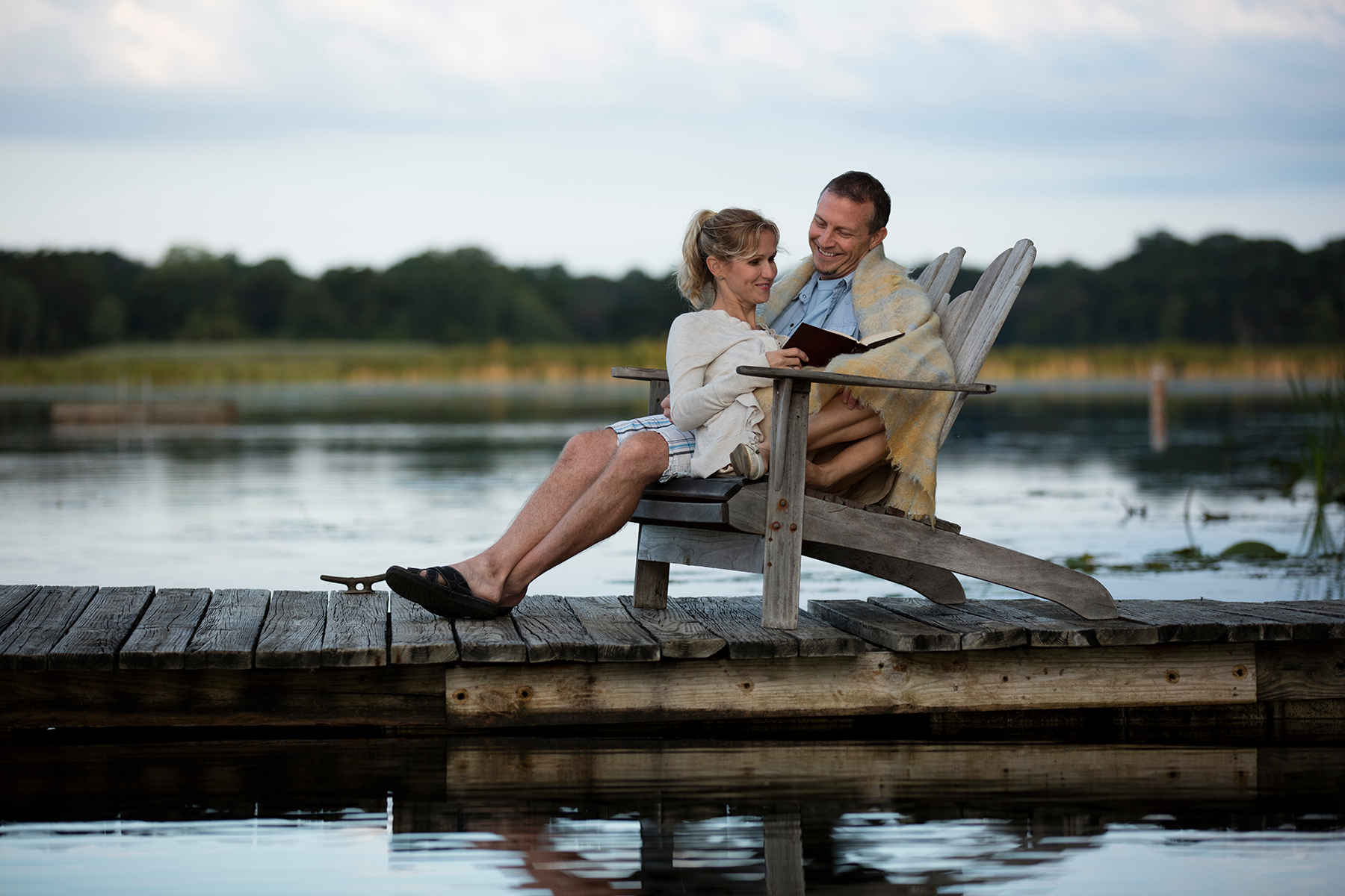 Couple sitting in chair on dock by water