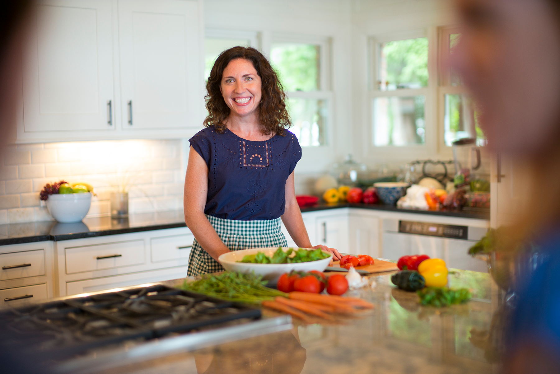 Female smiling in kitchen while preparing a salad